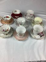 Top-down view of all 8 tea cups and saucers arranged with varying floral patterns and colors visible.