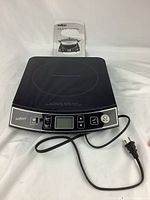 Front view of black Salton induction cooktop with digital control panel and power cord visible.