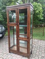 Full view of the solid wood display cabinet from front angle showing glass doors and wood frame.