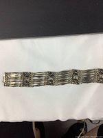 Full view of vintage sterling silver bracelet laid on white cloth showing the detailed rectangular panels and multiple narrow silver strands connection