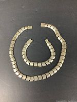 Necklace and bracelet laid flat in circular arrangement on black background