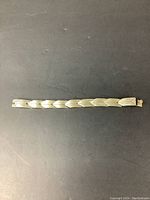 Top down view of the full length sterling silver bracelet showing geometric link pattern and clasp.