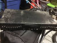 Front view of the AudioSource EQ-100 showing multiple sliders for bass, midrange, and treble, model and branding visible.