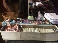 View of a large box filled with numerous collectible sports cards interior, showing thick stacks of cards organized inside the box with some cards displayed on top.