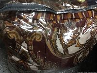 Close-up photo of king size comforter inside a clear plastic bag showing detailed paisley pattern.