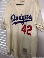 Front view of Dodgers jersey with number 42, showing button closure and overall cream color with visible signs of age and wear.