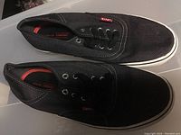 Side view of a pair of black Levi's sneakers showing the white sole, black canvas, and red Levi's logo tag on the side.