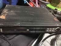 Magnavox black DVD player showing rust and dust on top surface.