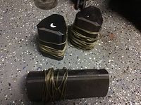 Two small Magnavox satellite speakers and one long center speaker placed on a black and gray speckled floor, wires wrapped around each speaker.