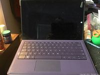 Close-up showing open Microsoft Surface tablet with built-in purple keyboard on table.