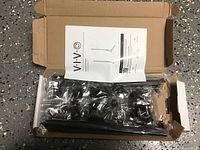 Box opened showing components of ViVo TV stand wrapped in plastic with instruction manual on top.