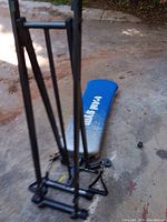 Photo showing the blue padded incline bench labeled Total Gym with black metal frame and vertical bars.