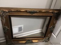Photo of vintage ornate wooden frame without glass, showing detailed decorative corners and center embellishments.