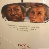 Close-up photo showing part of the poster featuring Morgan Freeman and Jessica Tandy's faces framed within a rearview mirror image, with tagline text below.