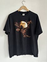 Full front view of black Harley Davidson T-shirt with eagle and flame graphic on front.