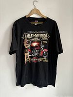 Front view of black Harley Davidson T-shirt with a large graphic of a red motorcycle and woman in retro outfit.