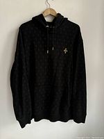 Front view of black OVO hoodie with subtle repeated logos and front kangaroo pocket.