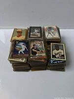 Multiple stacks of baseball cards shown with a mix of card designs and players visible. Many cards sleeved individually.