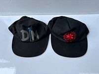 Pair of black vintage concert hats, Depeche Mode with blue flower and Red Hot Chili Peppers with red logo