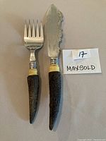 Full view of the 2 piece carving and serving set with dark textured antler handles and silver plated ends.