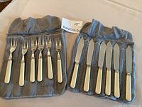 Full view of 6 forks with ivory handles and 6 knives with ivory handles in grey flannel sleeve, showcasing condition and quantity.