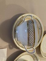 Close-up photo of a white china soup bowl with gold trim and turquoise medallion pattern on saucer