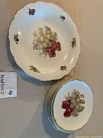 Photo showing one larger platter with cluster of red and white grapes and 10 matching smaller dessert plates stacked showing same grape design.