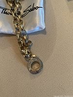 Close-up of Thomas Sabo sterling bracelet chain and round charm with 'THOMAS SABO CHARM CLUB' embossed.