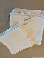 Stack of 13 large white linen napkins photographed from above showing size and texture.