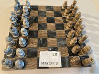 Full front view of the marble chess set with all pieces in standard starting positions on the board.