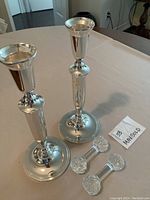 Pair of silver toned candlesticks with rounded bases and polished finish