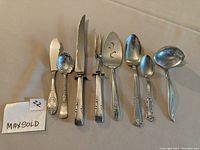 Photo of 7 vintage silver plated serving pieces including carving knife and fork, various ornate designs, some Rogers Brothers