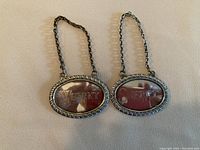 Front view of two oval metal bottle labels for whisky and sherry carafes, one labeled WHISKY.