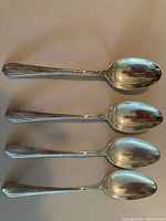 Four sterling silver teaspoons arranged side by side showing size and design
