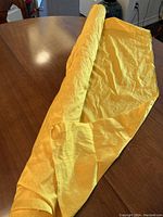 Yellow/gold Dupioni Thai silk fabric rolled out over a table, showing texture and condition.