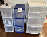 Front view of three plastic storage drawer units side by side on wooden floor.