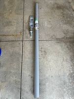 Full view of gray steel adjustable jack post disassembled with top and bottom plates and adjustment screw on concrete floor.