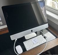 Front view of Apple iMac 21.5-inch desktop, with Magic Mouse and Magic Keyboard placed on desk