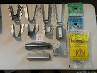 Top view showing galvanized steel metal brackets and braces, two rolls of metal strapping, a Wedge-Loc corner brace package, and wood connectors arranged on a table.