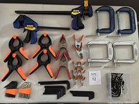 Overview of lot showing Irwin Quick Grips, spring clamps, Allen keys, and C-clamps arranged on table.