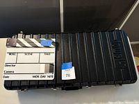 Closed black Lowel TO-83 hard case with director’s slate/clapper placed on top