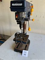 Front view of full drill press on table showing base, column, adjustable table and head assembly
