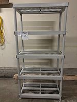 Front view of assembled five-shelf plastic shelving unit in light gray color with slatted shelves and vertical posts.