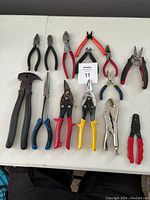 All fourteen pliers and cutters arranged on table showing various styles, colors, and sizes.