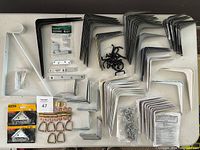 Overview of all metal brackets, tie down rings, and peg board hooks laid out on a table showing quantity and variety.