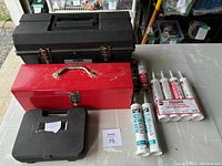 Photo of two toolboxes (one black Strong N' Tuff 22" toolbox, one red 19" metal toolbox), caulking and adhesive tubes, and a small black plastic case