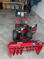 Front view of red Troy-Bilt Storm 1130 snow blower showing auger housing, tires, chute assembly and control panel.
