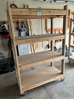 Full front angled view of a 4-tier wooden shelving unit with MDF shelves and locking caster wheels.