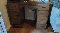 Full front view of vintage solid wood desk showing drawers on both sides and central kneehole space.