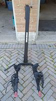 Front view of the Yakima 2 bike hitch mount rack leaning against a brick wall, showing the dual arms and securing straps.